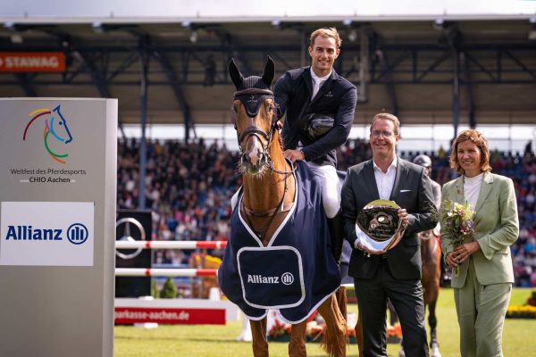 La foto mostra il vincitore dell'Allianz-Prize al CHIO Aachen, Richard Vogel, insiema a Oliver Leber e l'ALRV President Stefanie Peters.