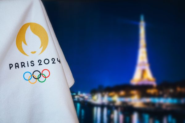Bandiera con logo delle Olimpiadi di Parigi 2024 con in sfondo la Tour Eiffel illuminata