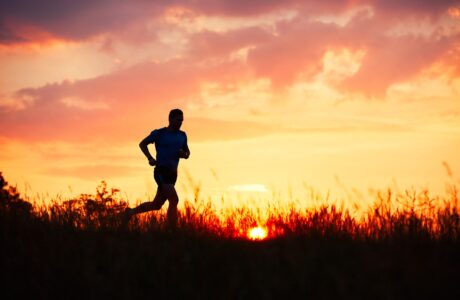 Silhoutte di un ragazzo che corre al tramonto in un sentiero di trail running