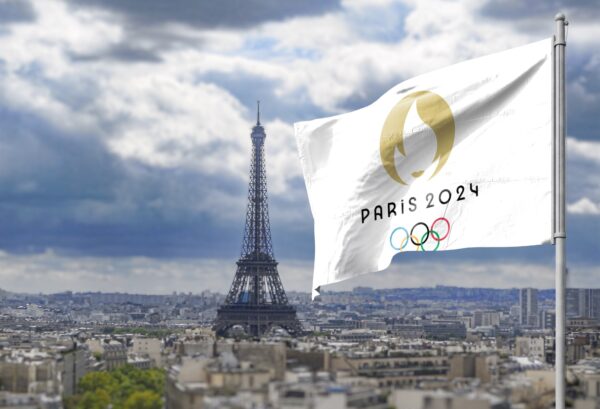 Tour Eiffel in sfondo e bandiera di Paris 2024 che sventola in primo piano